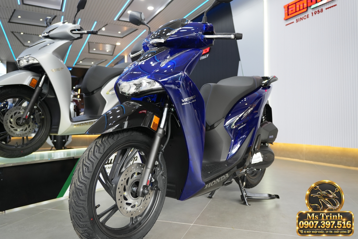 Honda SH150 Vetro Blue Sapphire nhìn ngang hướng đầu sang phải Honda SH150 Vetro Blue Sapphire nhìn ngang với đầu xe hướng phải, mâm đen và yên xám